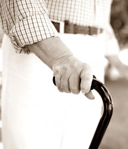 Close-up of disabled female hand holding cane with her doctor walking near by